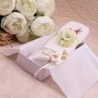 Asciugamano bianco chiuso da un giro di nastro e un bouquet di peonie avorio
