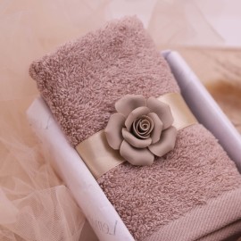 Un asciugamano in cotone pettinato da 620 grammi, avvolto da un nastro con rosa in porcellana