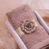Un asciugamano in cotone pettinato da 620 grammi, avvolto da un nastro con rosa in porcellana